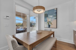 A dining area with a wooden table and bench, a pendant light, and a large abstract painting on the wall. - Luxury 5BR | Sleeps 16 | 1 Block to Beach & Boardwalk (Ocean City)