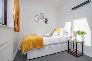 Ein Schlafzimmer mit einem Bett, einem Nachttisch und einem Fenster mit Vorhängen.