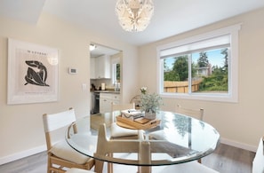 A dining area with a glass table, wooden chairs, and a view of the outdoors through a large window. - Cozy 3-bedroom townhome with fireplace and AC in lovely Bellevue (Bellevue)