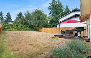 A backyard with a wooden deck, a red umbrella, and a barbecue area. - Cozy 3-bedroom townhome with fireplace and AC in lovely Bellevue (Bellevue)