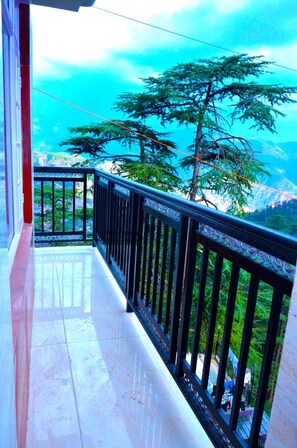 Ein Balkon mit Metallgeländer, der auf eine gebirgige Landschaft blickt.