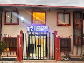 A building with a gated entrance, a sign reading 'TN TALARA NOVA,' and a red-tiled roof.