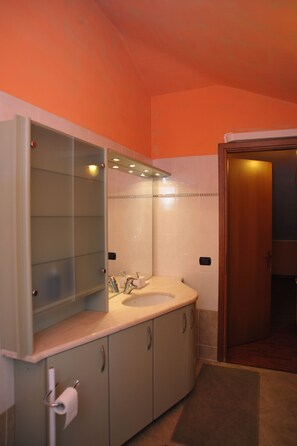 Un baño con lavamanos, espejo y armarios.