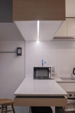 A kitchen with a microwave, a sink, and a wooden stool. - Study with a large window · Featured design (H06) (Providencia)