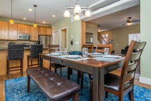 A dining area with a wooden table set for four, surrounded by chairs, a bench, and pendant lighting. - Spacious SLC Home | Hot Tub, Game Room, BBQ & Yard (Salt Lake City)