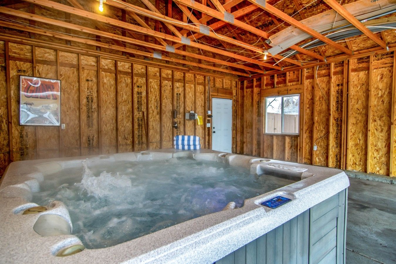 Un bain à remous dans une pièce aux murs en bois et dont la porte est visible.