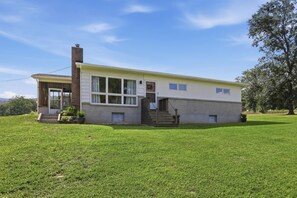 A single-story house with a covered porch, a staircase leading to the entrance, and a well-maintained lawn. - Mid Century-Modern Retreat Great Allegheny Passage (Cresaptown, MD)