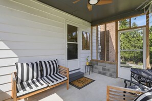 A covered porch with a wooden bench, a cushioned sofa, and a small table. - Mid Century-Modern Retreat Great Allegheny Passage (Cresaptown, MD)