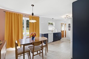 A modern kitchen with a dining area, featuring a wooden table, chairs, and a vase of flowers. - Mid Century-Modern Retreat Great Allegheny Passage (Cresaptown, MD)