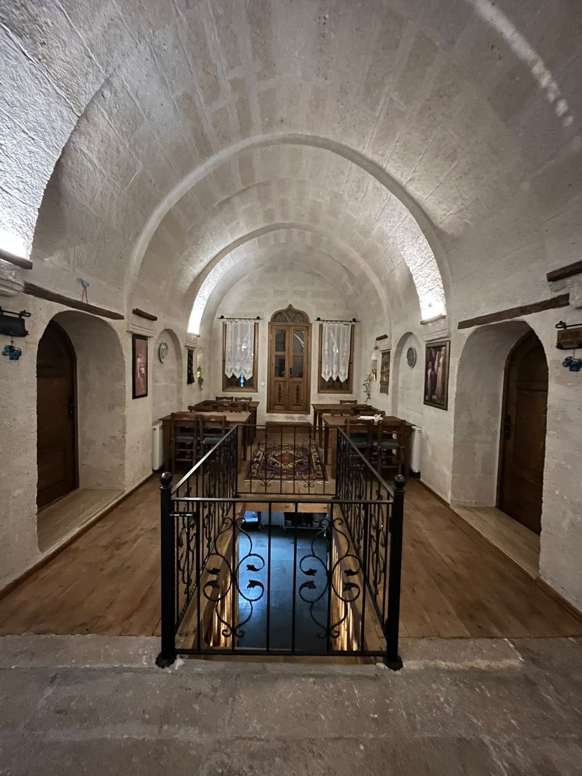 A spacious interior with arched ceilings, wooden furniture, and a central staircase.