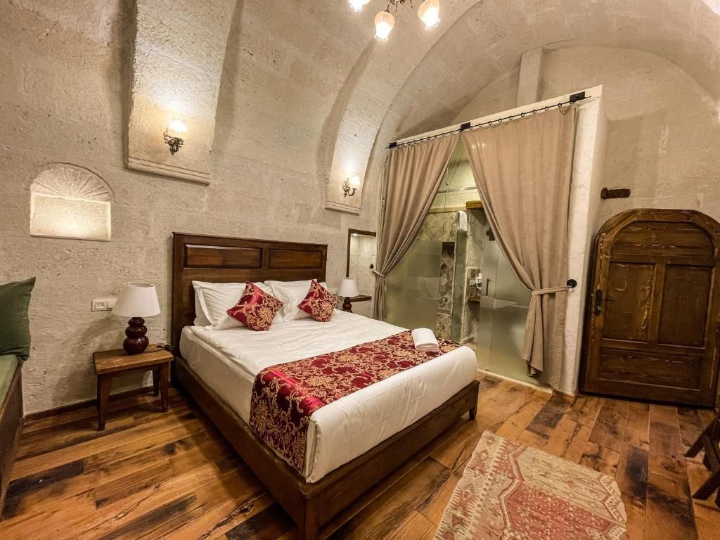 Un dormitorio con una cama de madera, una mesita de noche, una lámpara, un box de ducha de vidrio y una puerta.