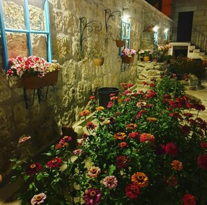 A stone wall with hanging flower pots and a variety of colorful flowers in the foreground.