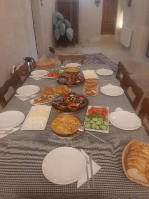Taula de menjador preparada per a una refecció, amb diversos plats i pa.