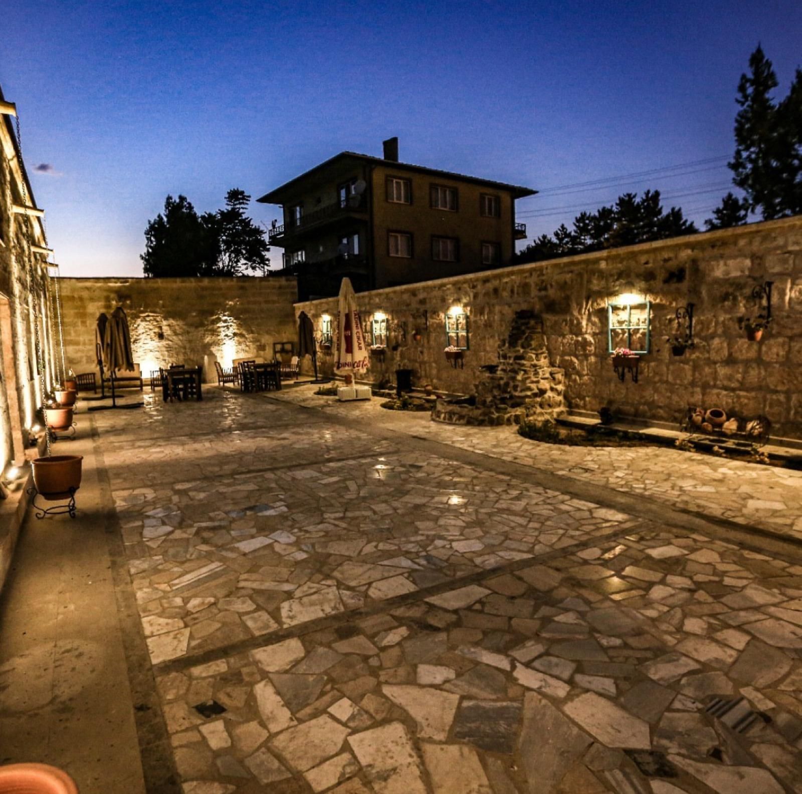 A courtyard with stone flooring, outdoor seating, and stone walls.
