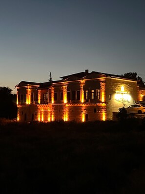 A large stone building with multiple windows and a car parked in front.