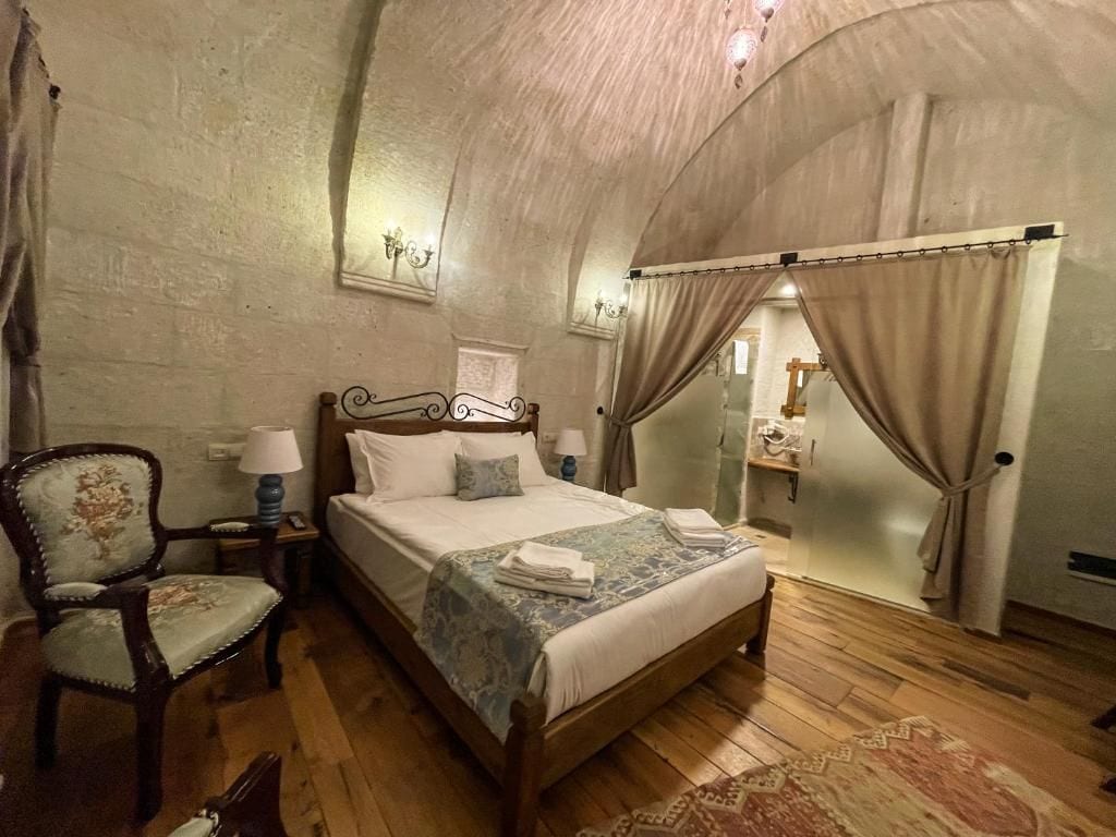 Un dormitorio con cama de madera, una silla, una mesita de noche y un espejo.