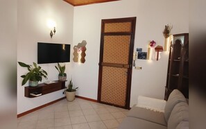 A living room with a flat-screen TV, a sofa, a wooden door, and decorative wall art. - Family-friendly apartment that welcomes pets, just 45 minutes from Bologna and Florence. (Baragazza)
