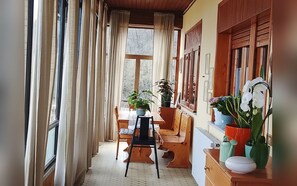 A narrow balcony with a wooden table and chairs, potted plants, and a view of trees outside. - Family-friendly apartment that welcomes pets, just 45 minutes from Bologna and Florence. (Baragazza)