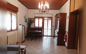 A dining area with a table and chairs, a chandelier, a fire extinguisher, and a window with curtains. - Family-friendly apartment that welcomes pets, just 45 minutes from Bologna and Florence. (Baragazza)