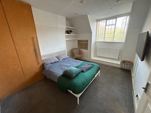 A bedroom with a bed, a wardrobe, a window with blinds, a chair, and a television. - Adorable bedroom house in wonderful Thornton Heath neighborhood (Thornton Heath)