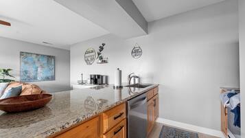 A modern kitchen with a granite countertop, stainless steel appliances, wooden cabinets, and decorative wall art.