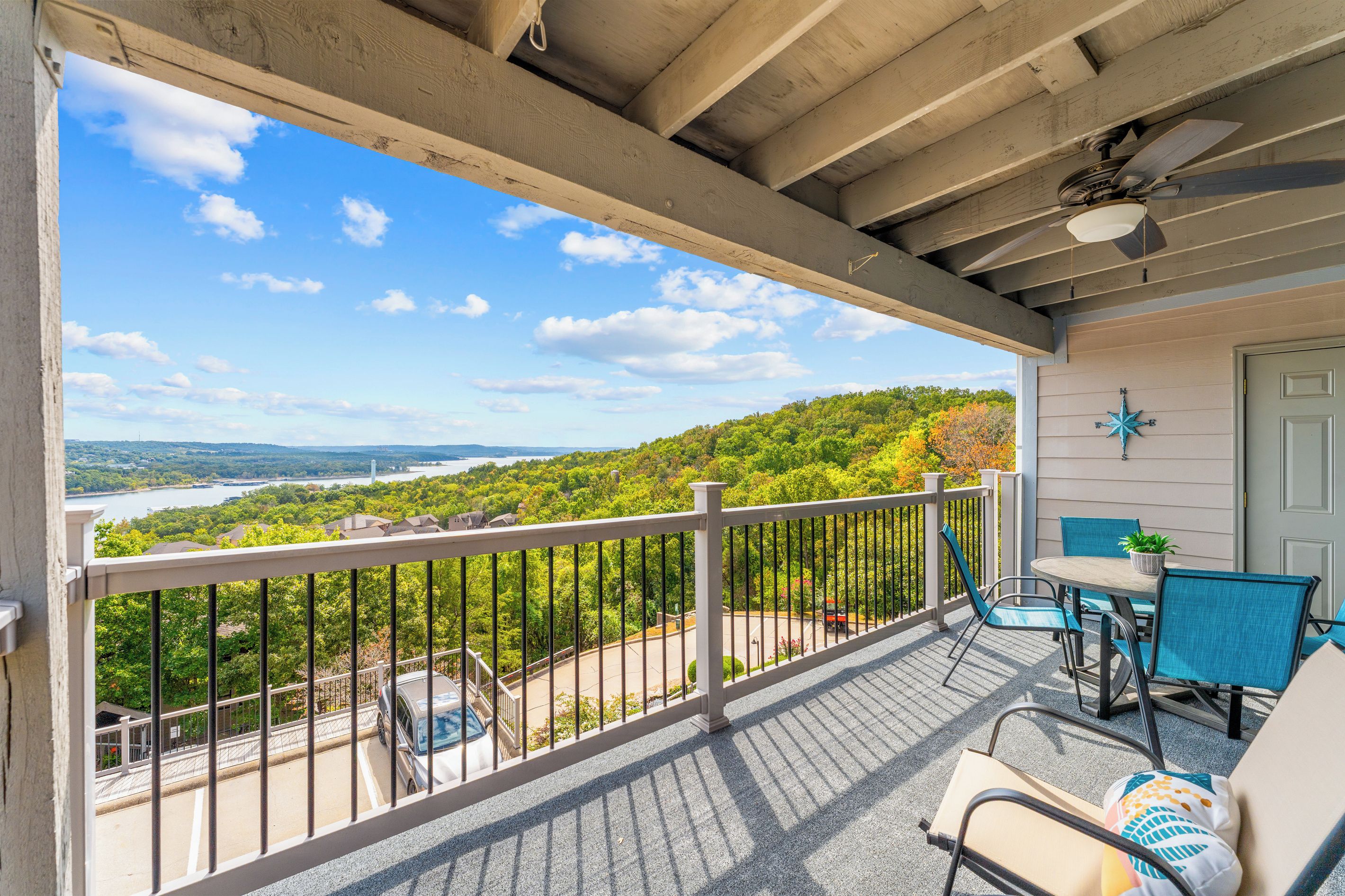 Ein Balkon mit Blick auf einen Fluss und Hügel, ausgestattet mit Stühlen und einem Tisch.