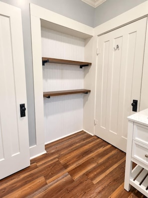 A hallway with white doors, wooden flooring, and built-in shelves. - The Biloxi Muse on Lameuse St. (Biloxi)