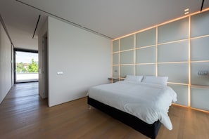A modern bedroom with a large bed, a sliding door, and a view of greenery outside. - Villa Bilor Luxe 6 by MMega (Subbiano)