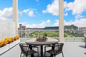 Een balkon met een tafel en stoelen, met uitzicht op een stadsbeeld en een rivier.