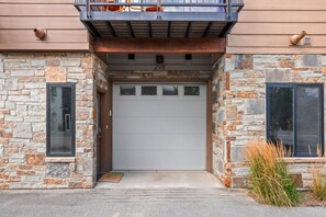 A stone facade with a garage door, a small window, and a door with a number '298' above it. - Winter Park Escape -Luxury, Hot Tub, Pet Friendly (Winter Park)