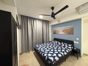 A bedroom with a bed, a ceiling fan, a wall-mounted air conditioner, and a painting. - Finland - 1BHK_Hiranandani Estate_Thane (Thane)