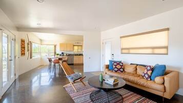 A modern living room with a leather sofa, a coffee table, and a dining area with chairs.