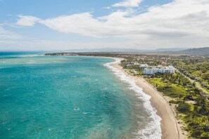 Une zone côtière comprenant une plage, l’océan et un quartier résidentiel avec des immeubles.