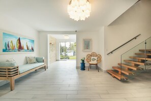 A modern interior with a wooden staircase, a bench, a painting, and a door leading to an outdoor area. - Amazing Beachfront Villa w Chef Maid at Cabarete (Sosúa)