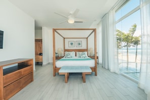 Une chambre à coucher avec un lit à baldaquin, un ventilateur de plafond et une vue sur la plage.