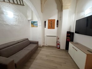 A living room with a sofa, a flat-screen TV, a radiator, and a fire extinguisher. - Maison Étoile (Lecce)