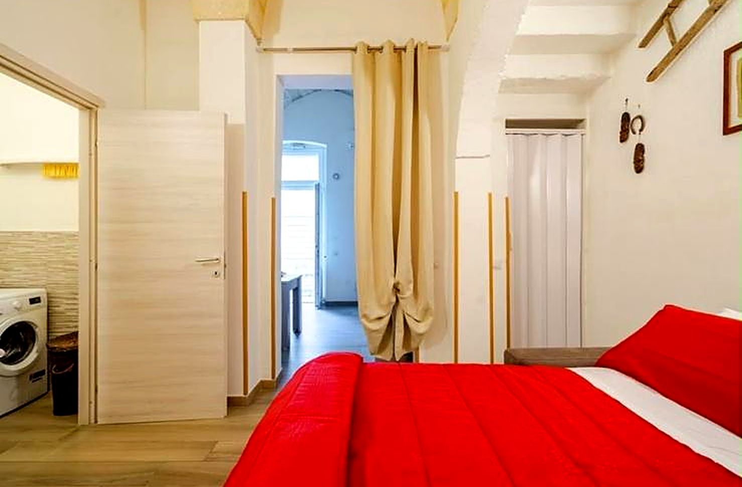 Une chambre d’hôtel équipée d’un lit, d’une machine à laver et d’une porte donnant sur un couloir.