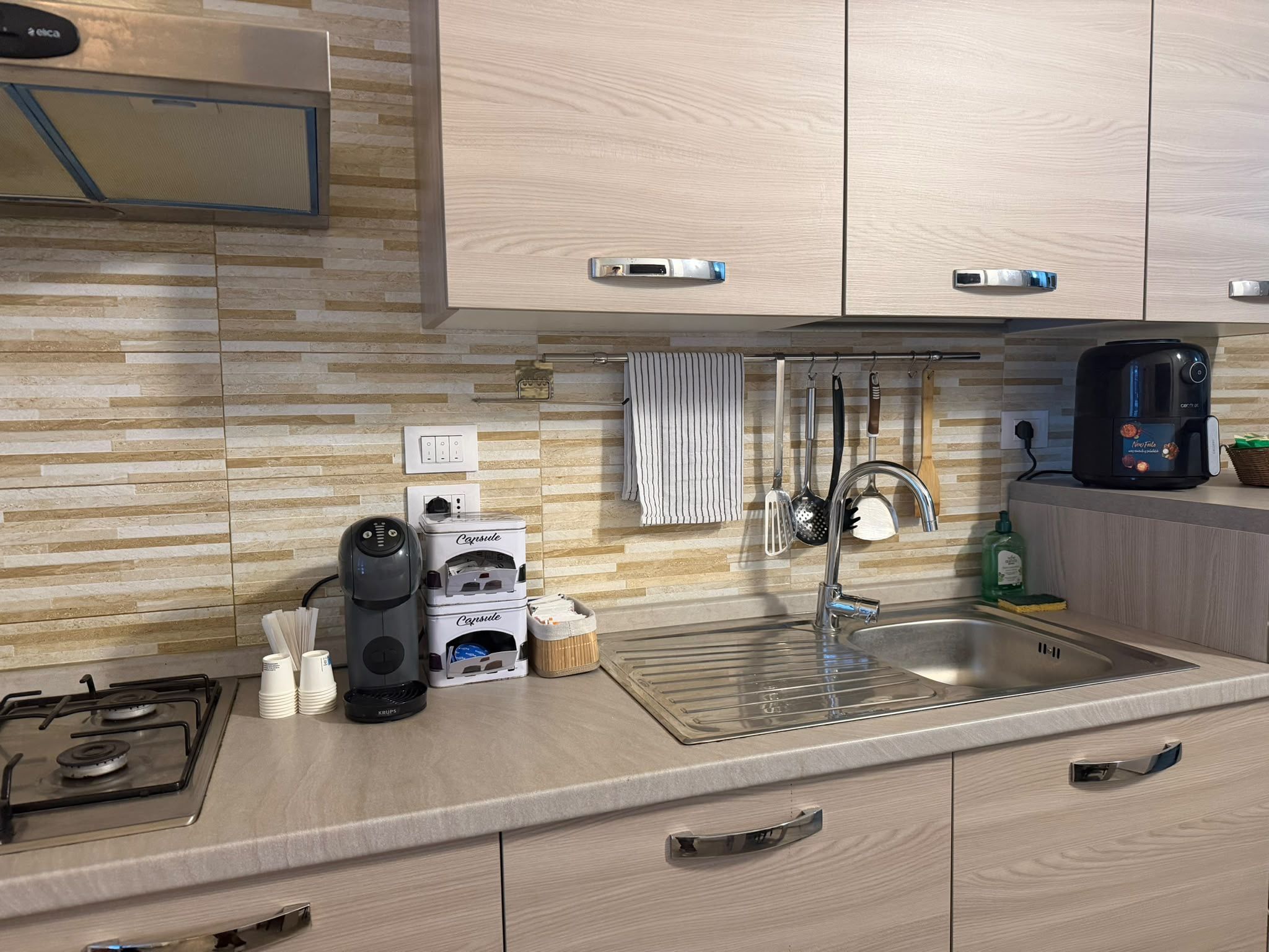 A modern kitchen with a gas stove, coffee maker, and a sink.