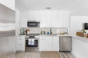 A modern kitchen with white cabinetry, stainless steel appliances, and a built-in dishwasher. - Two bedroom house in quaint Dania Beach on a canal and next to airport (Dania Beach)