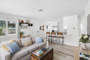 En moderne stue med sofa, sofabord og et spiseområde med stole.