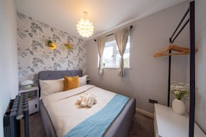 Un dormitorio con cama, mesita de noche, lámpara y una lámpara colgante.