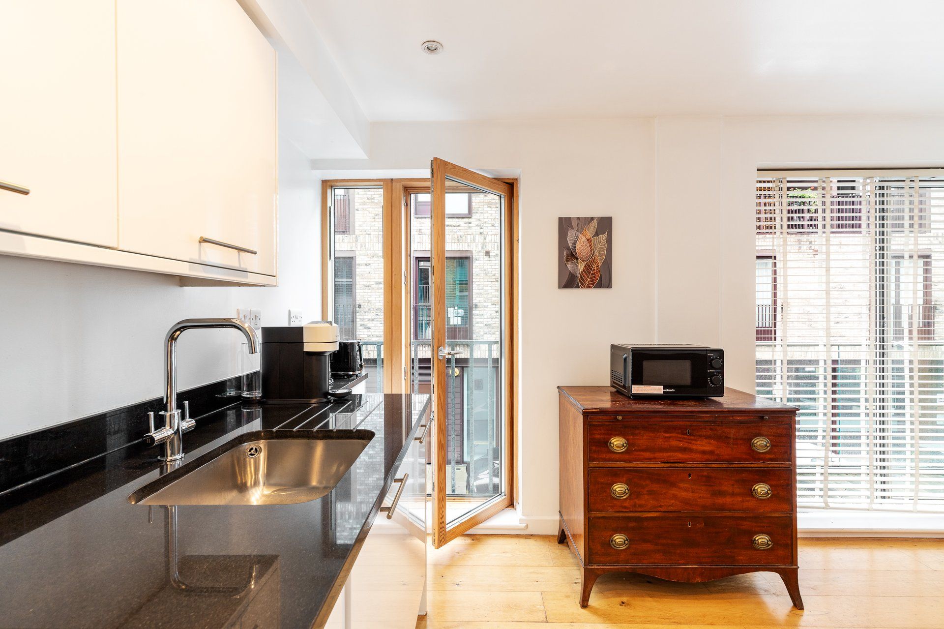 A modern kitchen with a built-in sink, a coffee machine, and a microwave on a wooden dresser.