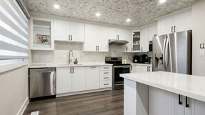 A modern kitchen with white cabinets, stainless steel appliances, and a marble backsplash. - Brand New - Private Renovated Estate - Secluded! (Brampton)
