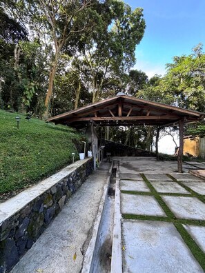 A covered outdoor area with a stone wall and a concrete pathway.