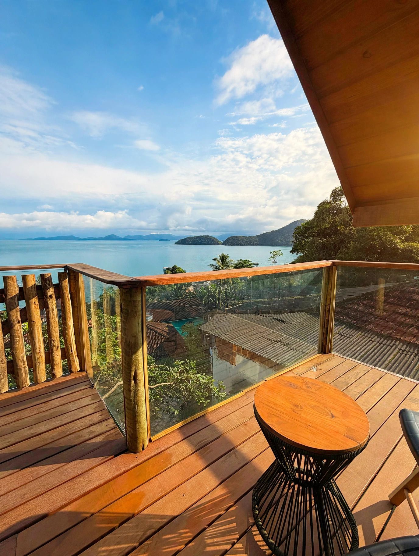 A wooden deck with a glass balustrade overlooking a body of water and distant islands.