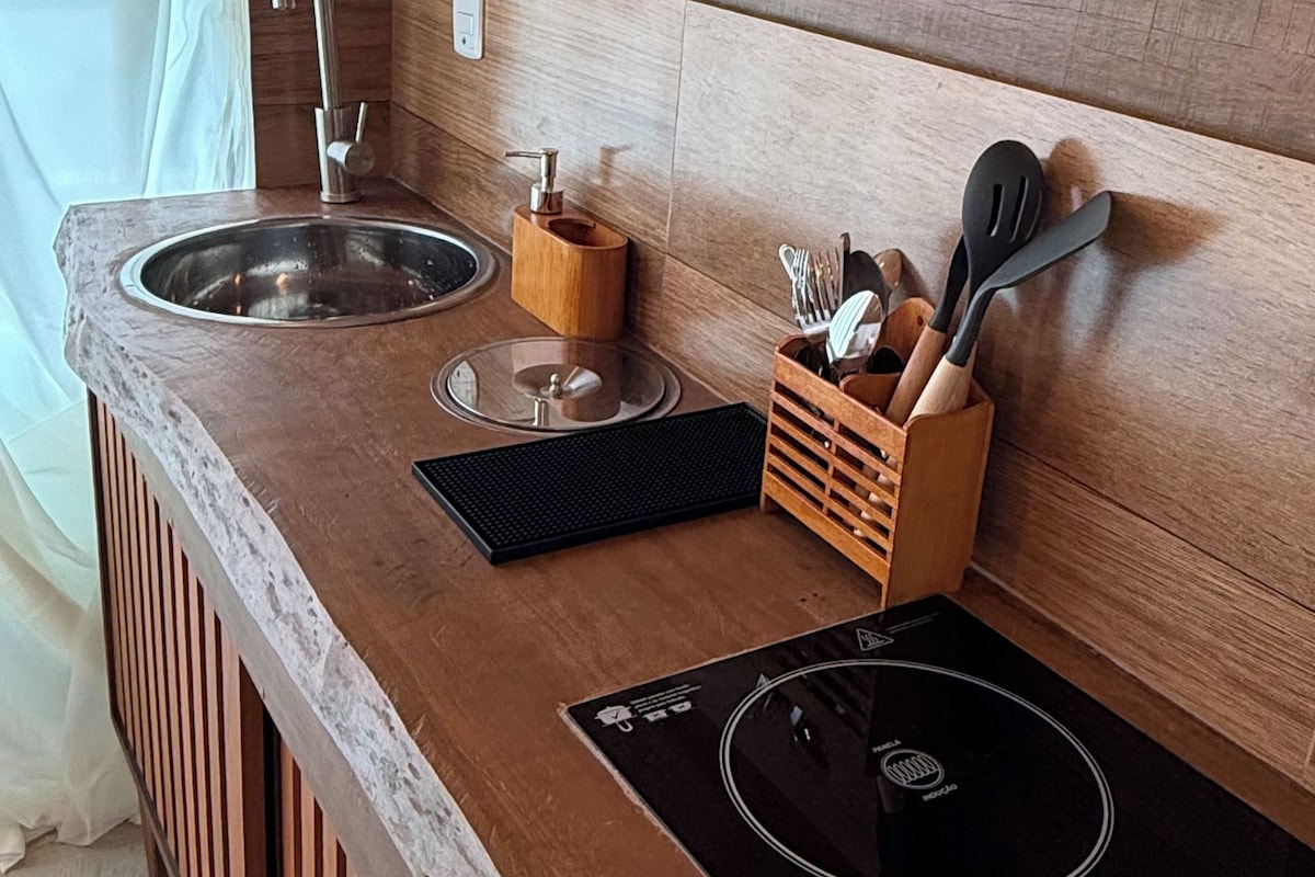 Una cocina compacta con un lavamanos, grifo, encimera de madera y una placa de inducción integrada.