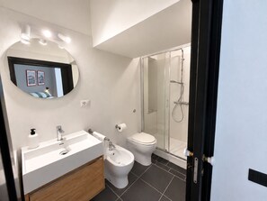 Un bagno moderno con lavandino, bidet, wc e box doccia in vetro.