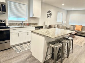 A modern kitchen with white cabinets, granite countertops, stainless steel appliances, and a central island with bar stools.