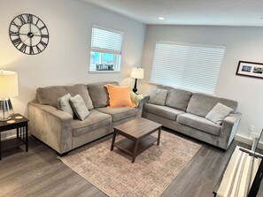 A living room with two grey sofas, a wooden coffee table, and a patterned rug.