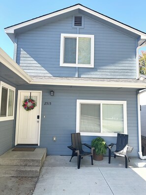 A two-story house with a front door, a number '2515' above the door, and two chairs outside.